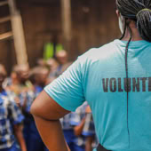 A volunteer interacts with children in a village school setting, fostering community support and development.