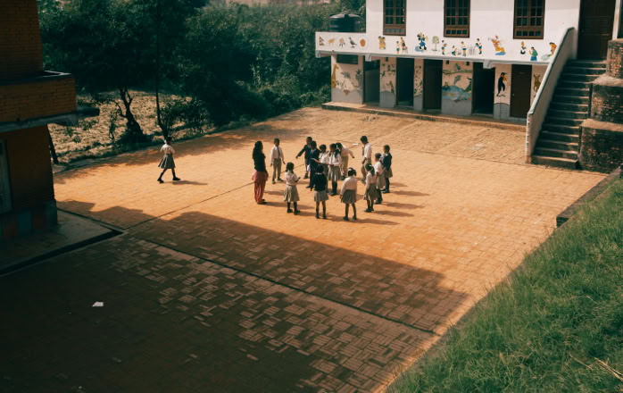 Group of children playing together on a sunny day in a school yard with murals outside.